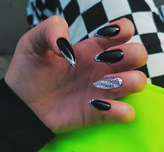 a hand with long nails with black and silver glitter