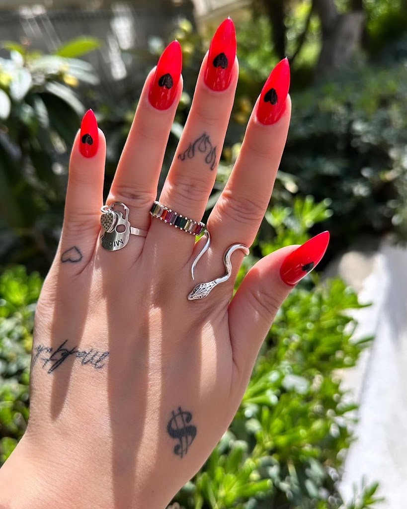 Pointed red nails each with a black heart in the centre