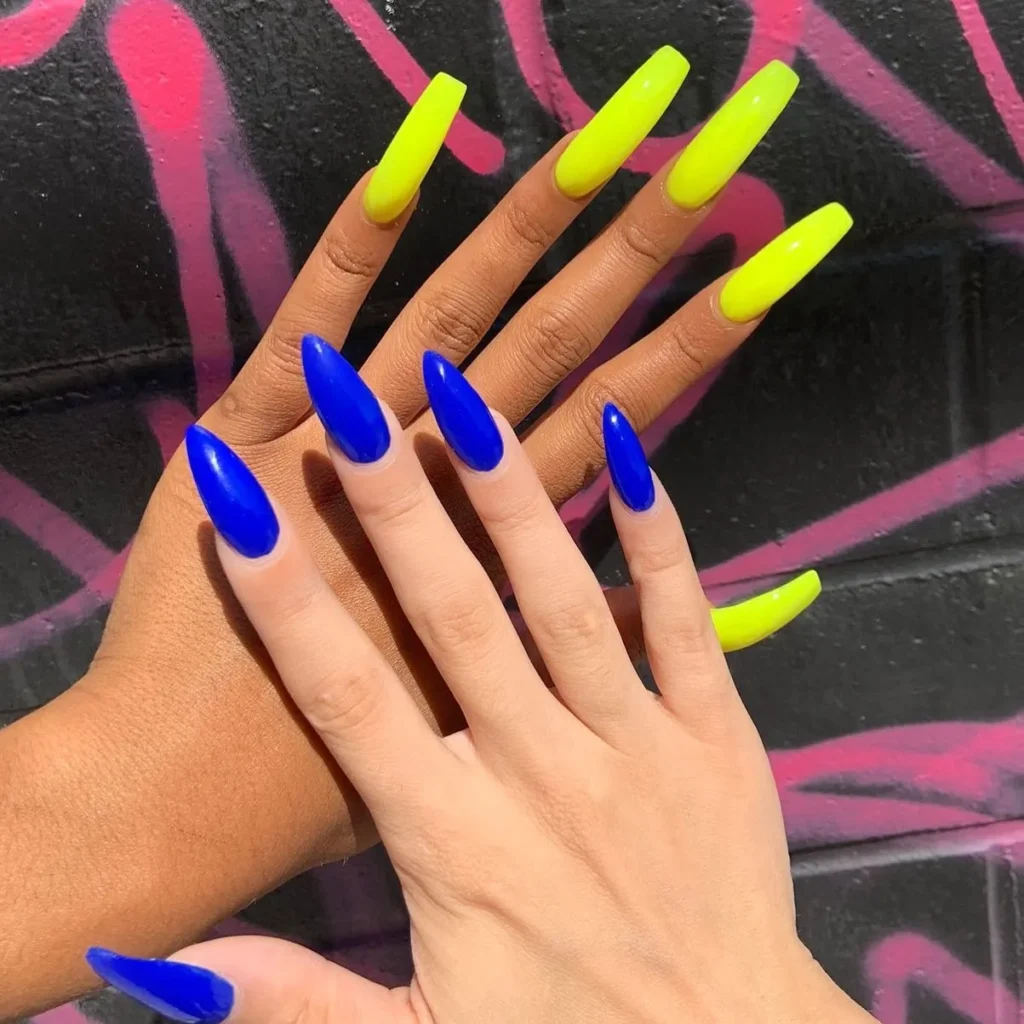 Two hands; one with bright blue and other with bright yellow nails