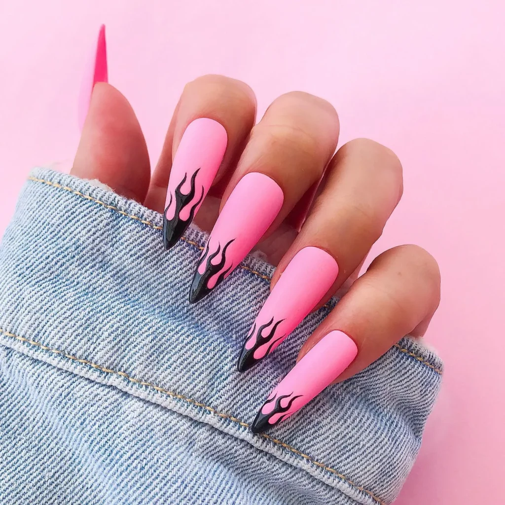 long, almond-shaped nails painted in a soft pink color with flame nail art in black colour Black.