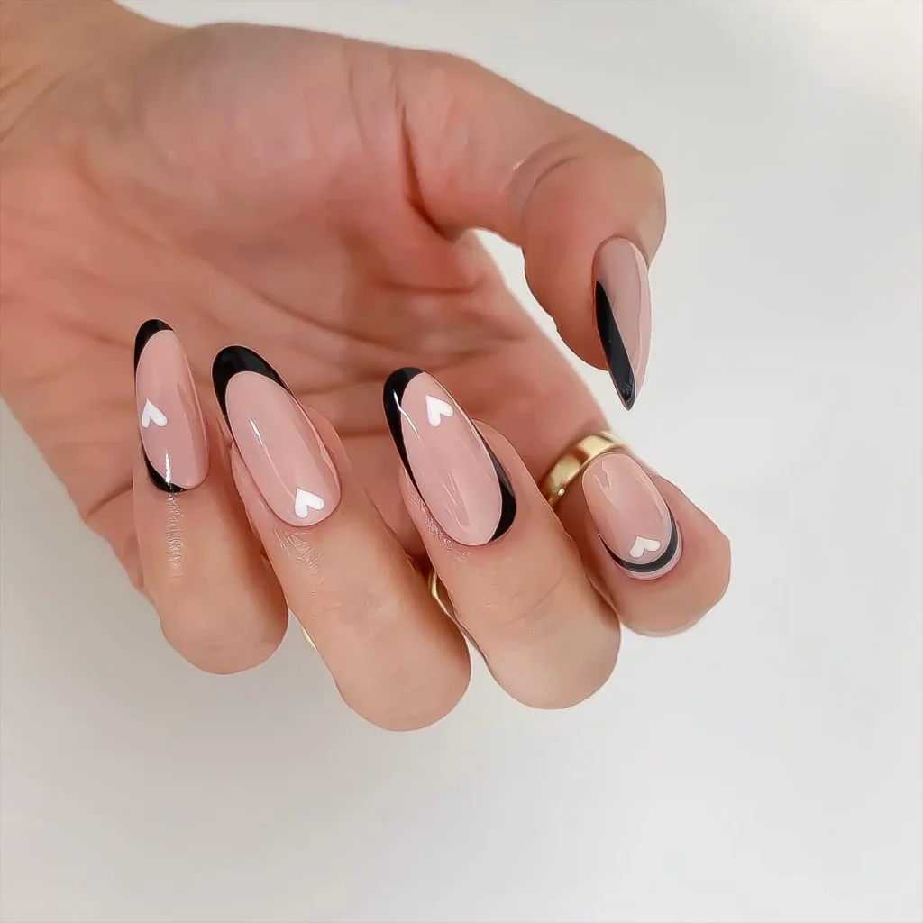 long almond-shaped neutral pink nails with black french tip and white hearts  