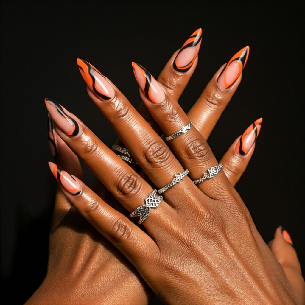 a close up of hands with orange and black abstract nails