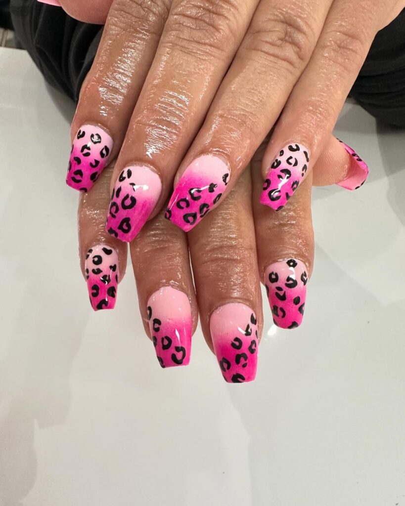 Ombre pink nails with black leopard spots.