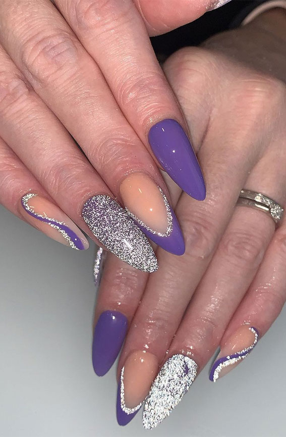 Long stiletto nails with solid purple and negative space designs created with silver glitter outlines