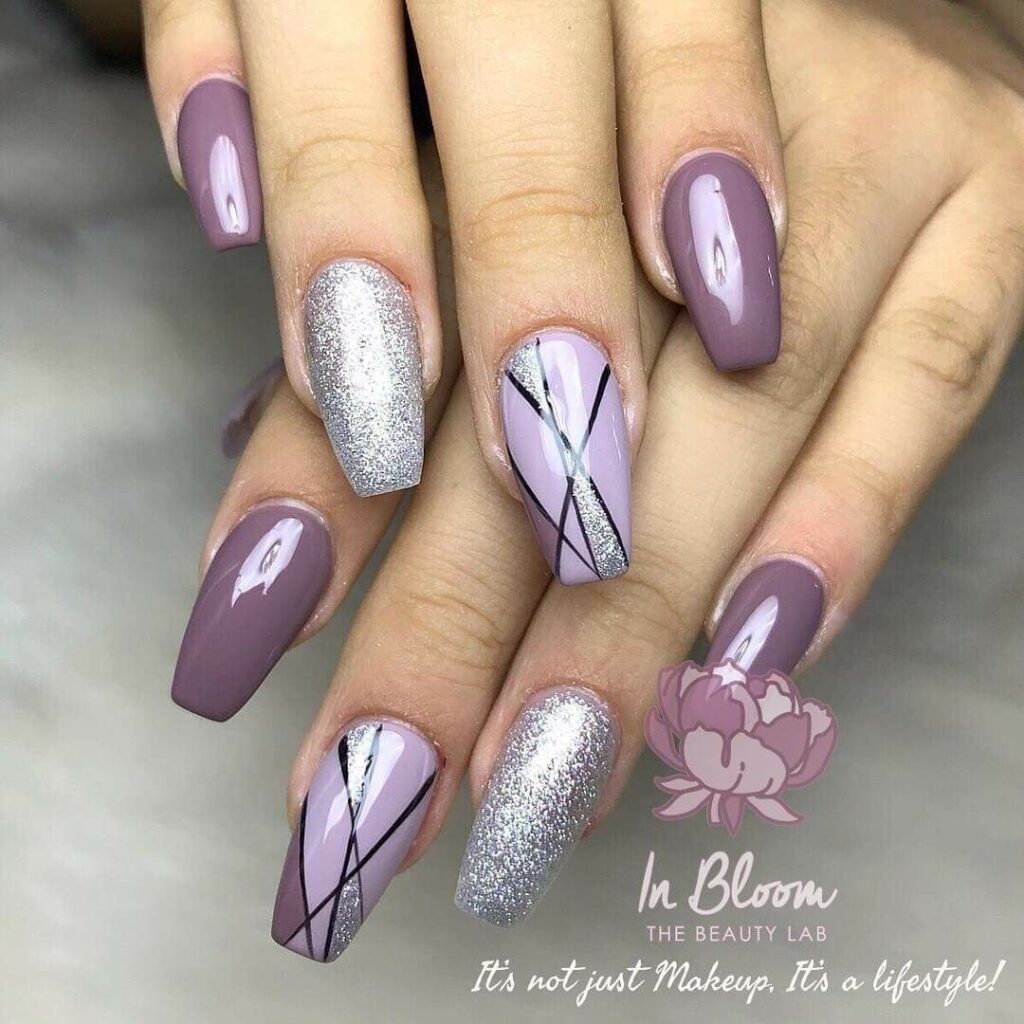 Muted purple nails with black geometric lines and a silver glitter accent nail