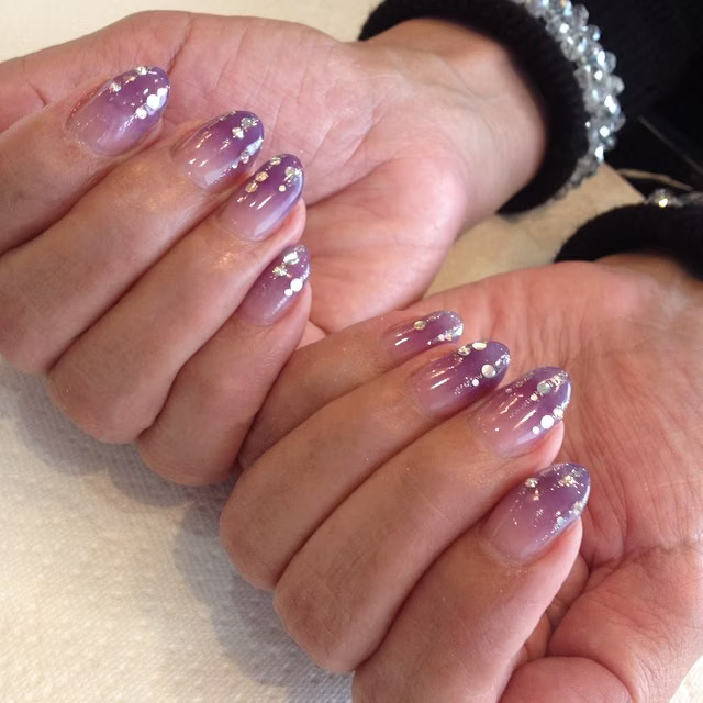 Short rounded purple ombré nails with scattered silver polka dots