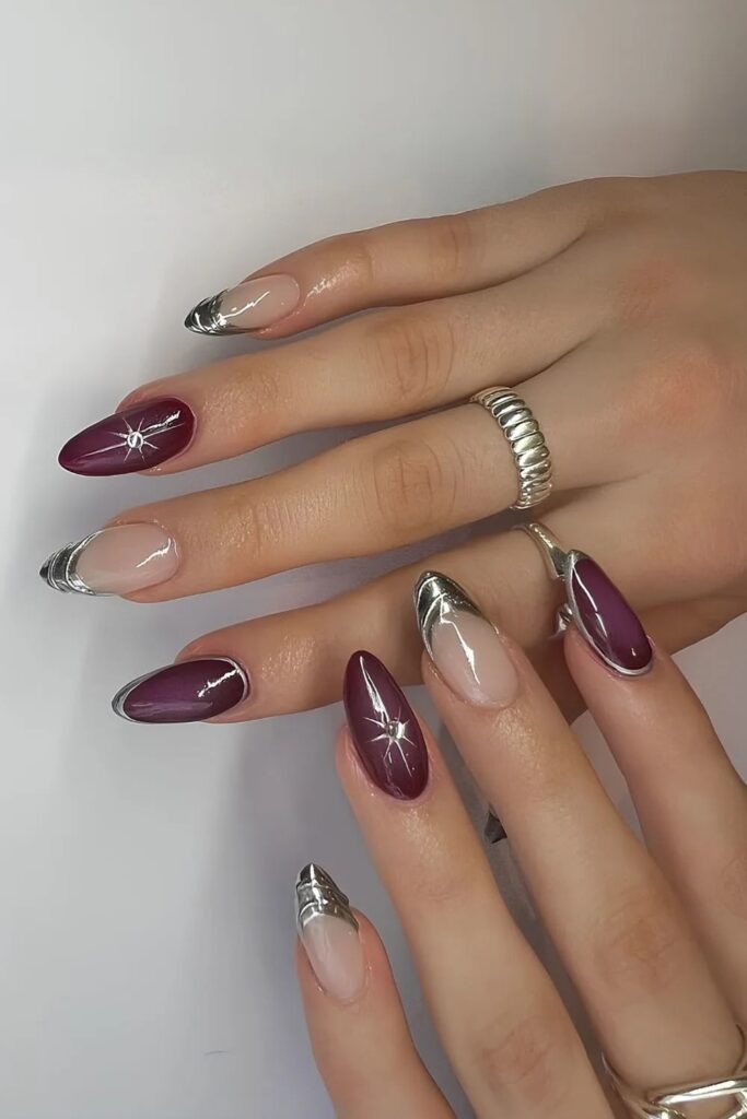 Stiletto nails with deep purple base, silver chrome French tips, and tiny silver starburst details