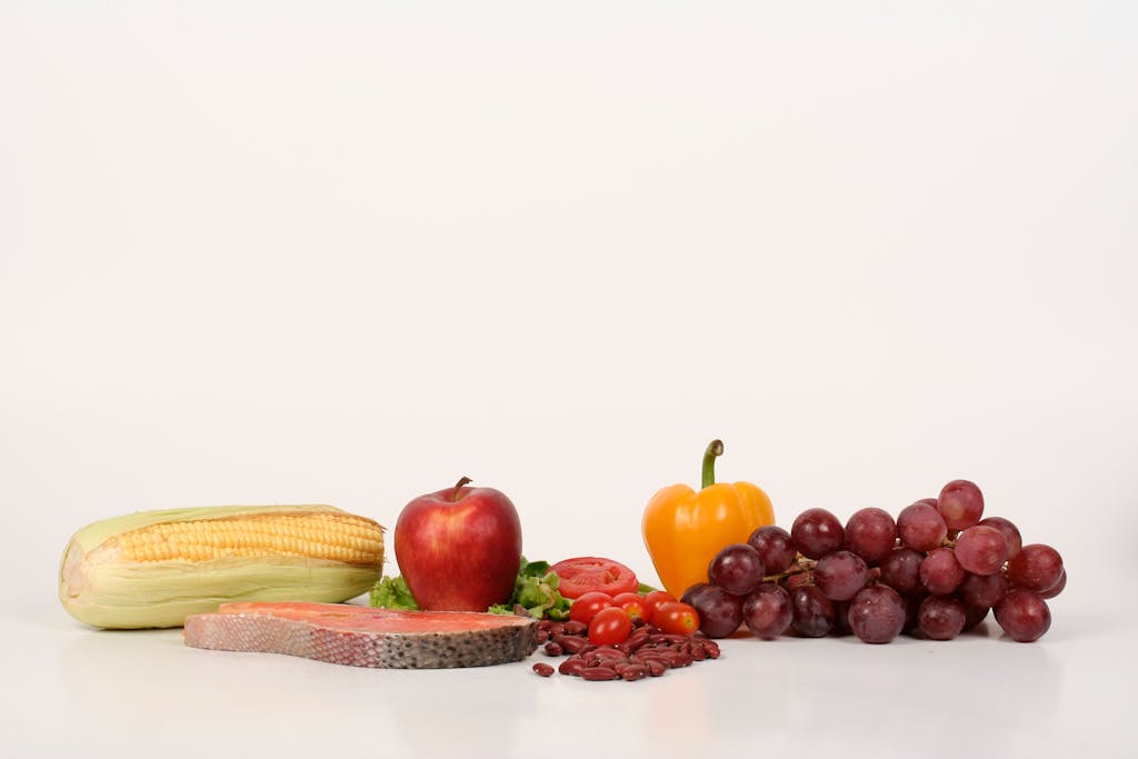 Vibrant display of fruits, vegetables, and salmon on a white background, ideal for food and health themes.